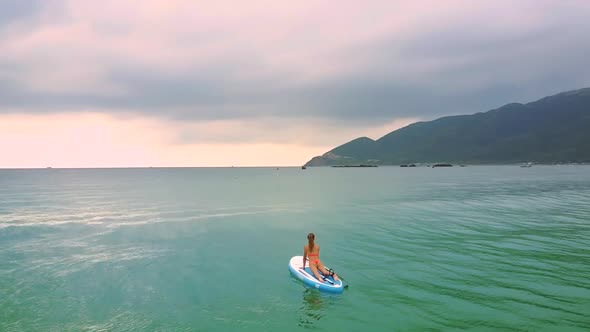 Waves Carry Blond Woman on Paddleboard To Open Ocean