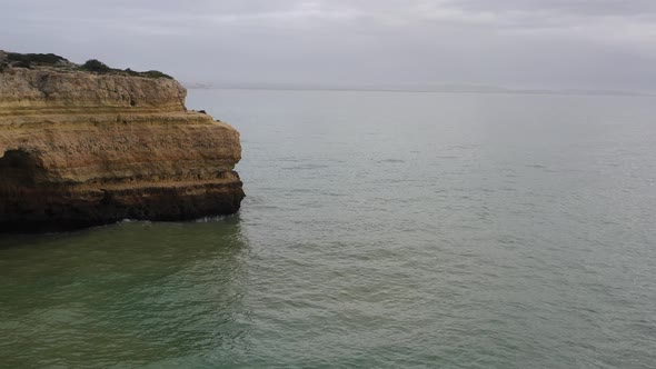 Rocky cliffs in Fontainhas beach of South Portugal appearing from the side, Aerial dolly in reveal s