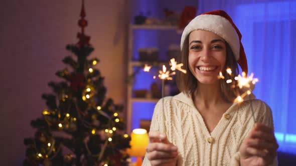 Close Up Face Happy Smiling Woman in Santa Hat with Burning Sparklers at Christmas Eve or New Year