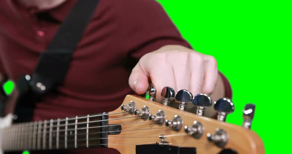 Mid section male musician adjusting tuners