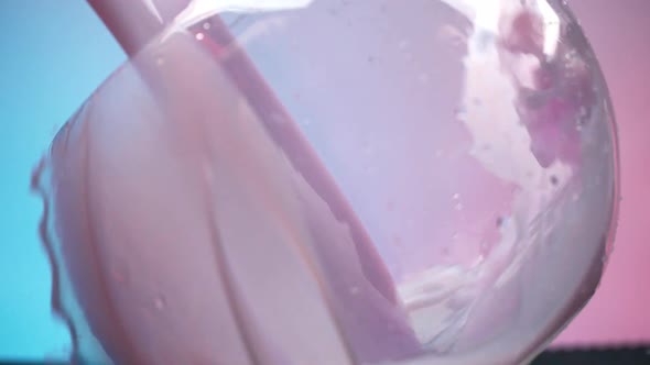 Delicious berry drinking yoghurt is poured into a transparent container and forms a beautiful wave