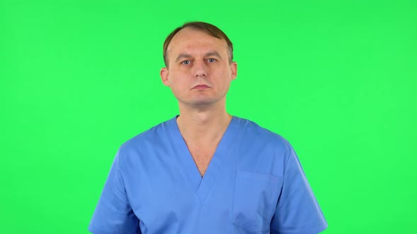 Medical Man Listens Attentively and Nods His Head Pointing Finger at Viewer. Green Screen