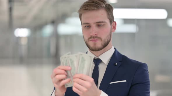 Happy Young Businessman Counting Dollars at Work