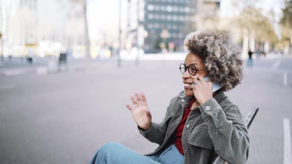 Cheerful adult African woman wearing casual clothes talking by mobile