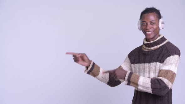 Young Happy African Man Pointing Finger and Showing Something Ready for Winter