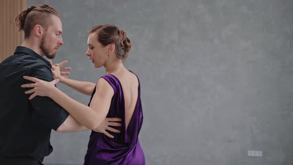 Close Shot of Couple Dancing Tango in Grey Studio Against Large Windows