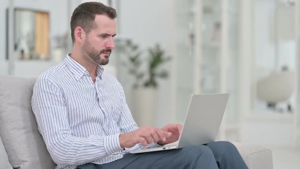 Young Man Reacting to Loss on Laptop at Home