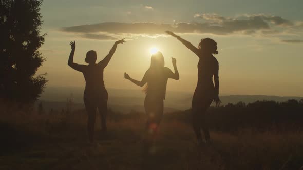 Silhouette of Elegant Carefree Women Having Fun Dancing Gracefully on Mountain Top at Sunset