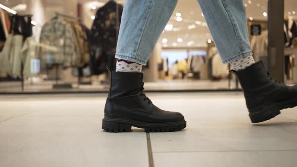 Woman in Boots Walks Near Clothes Shops in Shopping Centre