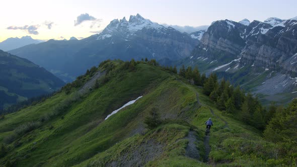 Mountain biker rides down a scenic ridge at dusk