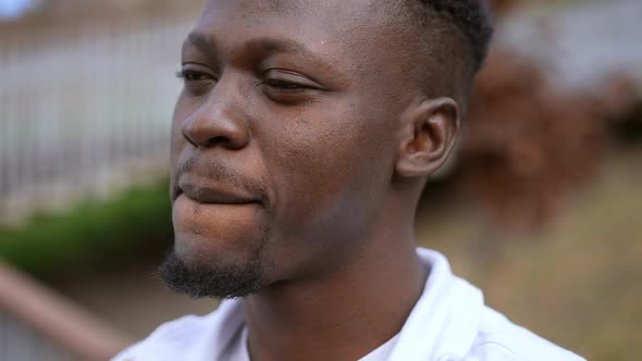 Headshot of Satisfied Young African American Man Talking and Looking at Camera Standing Outdoors