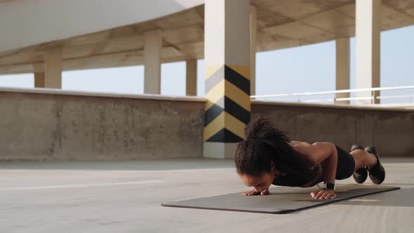 A strong american woman doing push-ups on a yoga mat