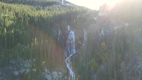 Drone approaching a big set of cascades where sunlight crosses the landscape at sunrise in Alberta,