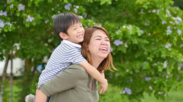 Happy Asian Mother Playing With Her Son In The Park