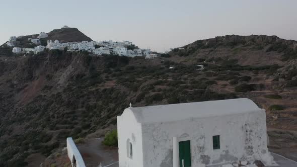 Flight Over Small Town Church on Greek Island Milos at Dusk