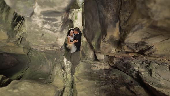Groom with Bride Standing in Cave of Mountain Hills. Wedding Couple in Love