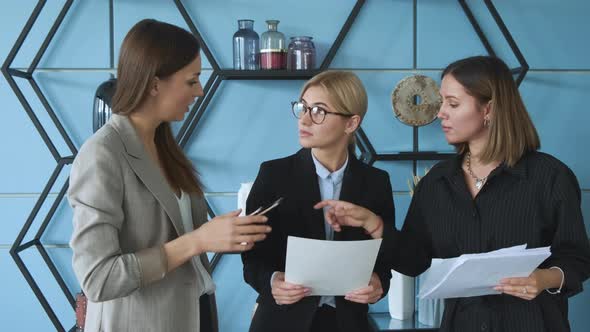 Young girls stand in the office and check documents. Three girls cheking their documents 