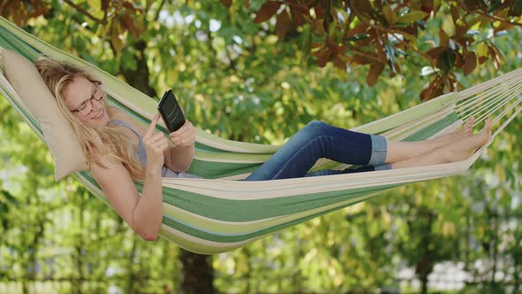 Smiling blonde woman with eyeglasses using smartphone