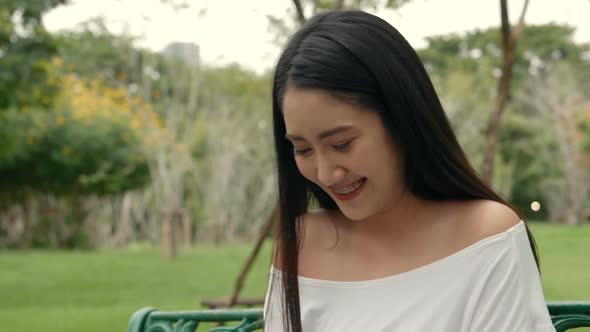 Young Asian woman using laptop at a public park.