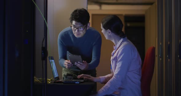 Diverse female and male it technicians using laptop checking computer server