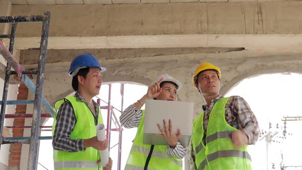 Architects and Engineers and Builders Holding a blueprint discussing building construction
