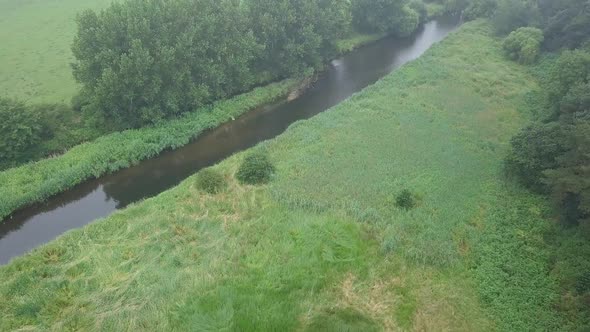 Aerial overfly and view of quiet river and surrounding trees