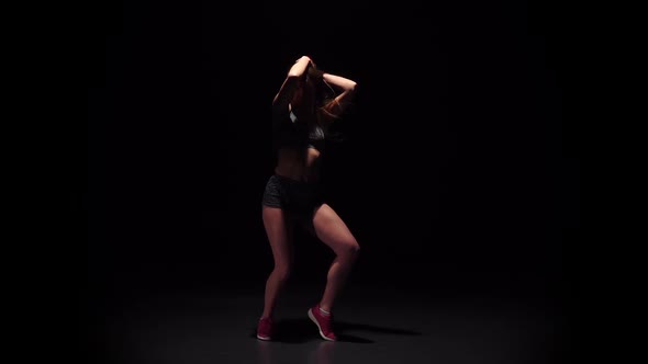 Woman Dancing Hip-hop Movement in Dark Studio Face To Viewer