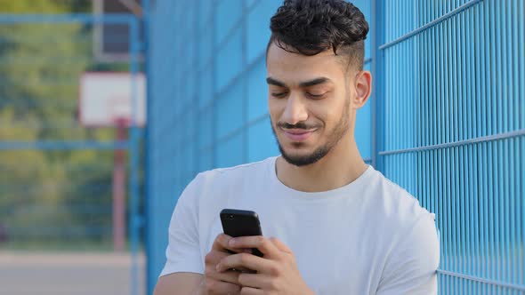 Young Middle Eastern Arabic Athlete in Summer Sportswear Holding Mobile Phone Using Virtual App