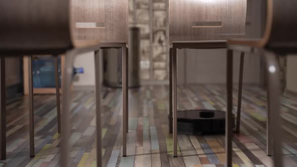 Robot Vacuum Cleans Between Chairs in the Dining Room