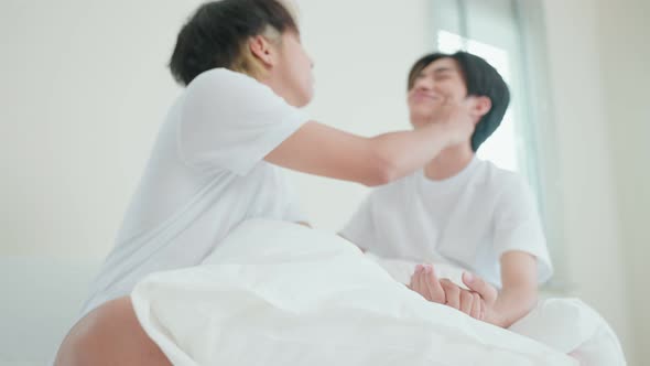 Attractive LGBTQ couple in pajamas, feel happy after wake up in morning and touch cheek of boyfriend