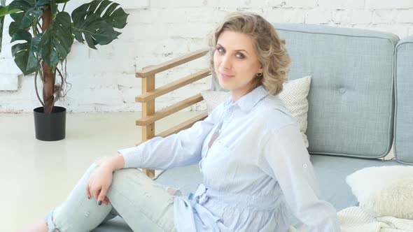 Young Blonde Woman Sitting On Sofa And Posing For Photos, Girl In Casual Clothes Sits On Sofa