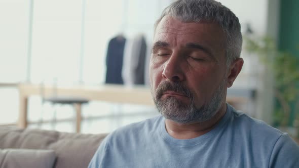 Portrait of a Depressed Elderly Man Sitting Alone on a Sofa