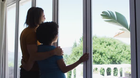 Mixed race couple looking out of the window at home