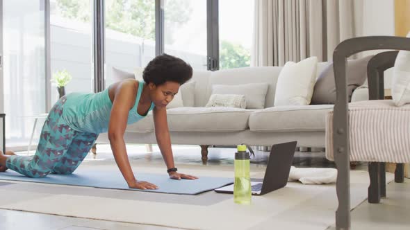 Happy african american wearing sportswear, exercising, using laptop