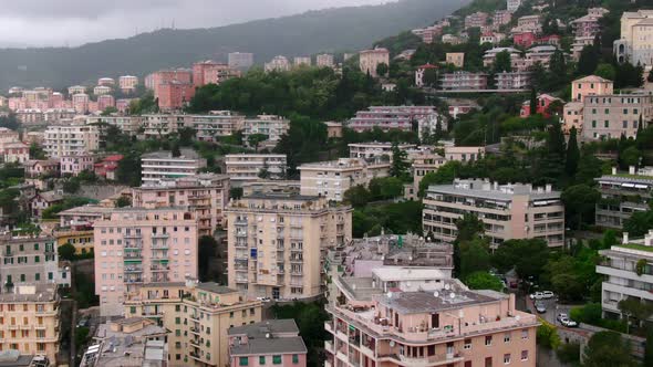 Cityscape of Genoa with forestry hilly landscape on foggy moody day, aerial view