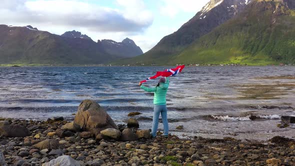 Woman with a Waving Flag of Norway on the Background of Nature