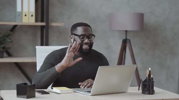 Black Guy Waves His Hand Into a Laptop and Communicates Via Video Link in Casual Clothes at Home