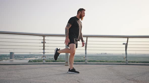 Man Warms Up Legs Preparing for Intensive Train at Sunrise