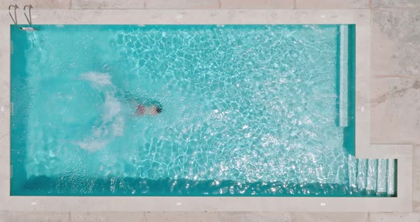 View From the Top As a Man Dives Into the Pool and Swims