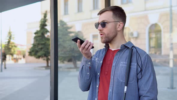 A Blind Man Speaks on the Phone at a Stop Bus