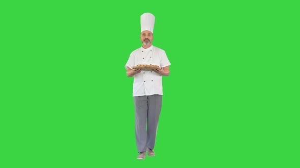 Senior Cook with a Pizza in Hands Walking on a Green Screen Chroma Key