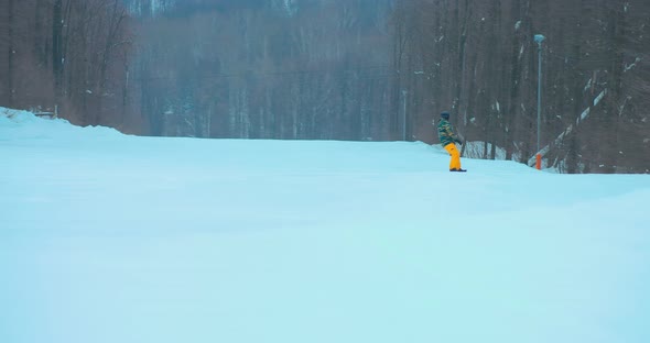 Professional Athlete Snowboarder Slides Down the Slope. Man Rides a Board on a Snowy Mountain