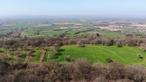 Aerial forward shot of Hembury Fort with the backdrop of the East Devon Countryside