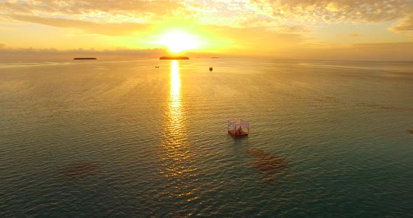 Aerial drone view of a man and woman having dinner on a floating raft boat at sunset