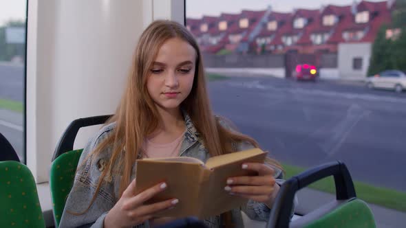 Portrait of Attractive Young Adult Woman Sitting at Empty Subway Train and Reading Interesting Book