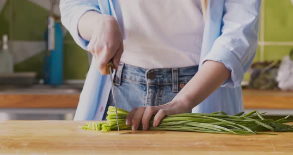 Woman Grinding Fresh Green Onions on Cutting Board