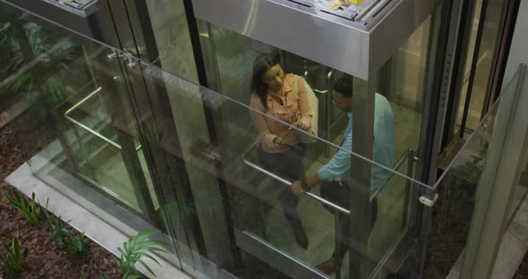 Video of diverse businesswoman and businessman talking in elevator