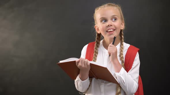 Dreamy Little Schoolgirl Writing in Notebook