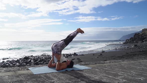 Woman in Sport Clothes Practicing Yoga and Meditating on Beach in Morning