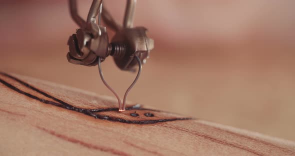 Woman making pyrography on wood, decorating a buddhist prayer wheel